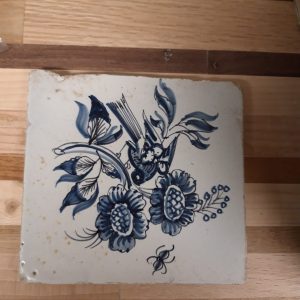 Antieke Delfts blauwe tegels met vogel bij bloemen en een insect