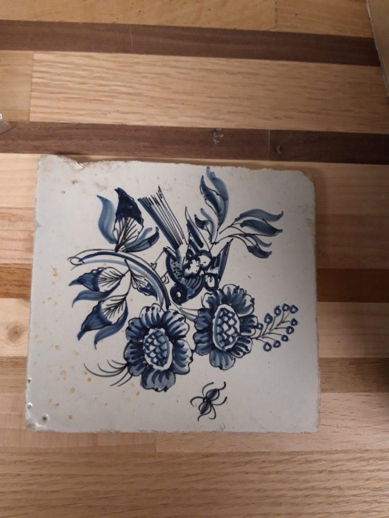 Antieke Delfts blauwe tegels met vogel bij bloemen en een insect